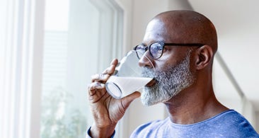 Mann drikker fra glass og ser ut vinduet