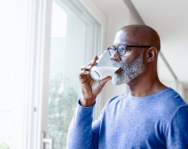 Mann drikker fra glass og ser ut vinduet