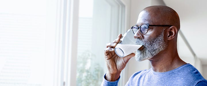 Mann drikker fra glass og ser ut vinduet