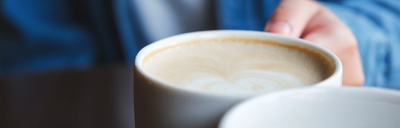 Nærbilde av hånd som holder en kaffekopp