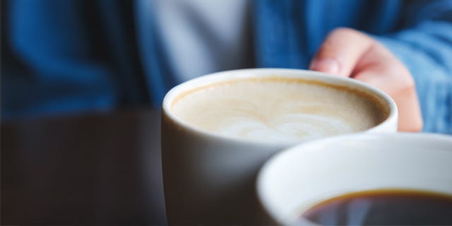 Nærbilde av hånd som holder en kaffekopp