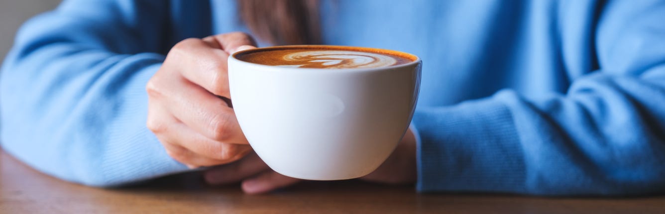 Nærbilde av person som løfter kaffekopp